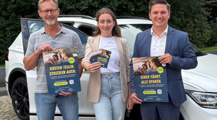 Ingo de Vries (Klimaschutzmanagement), Sonja Wolke und Geschäftsführer Jelto Müller (Wirtschaftsförderung Landkreis Aurich GmbH) stehen vor einem Auto und halten Werbeplakate für das Angebot "PENDLER"