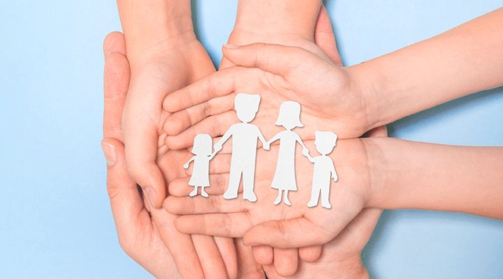 Symbolbild: 6 Hände von zwei Erwachsenen Person und einem Kind halten eine Papiersilhouette einer Familie die sich die Hände hält.