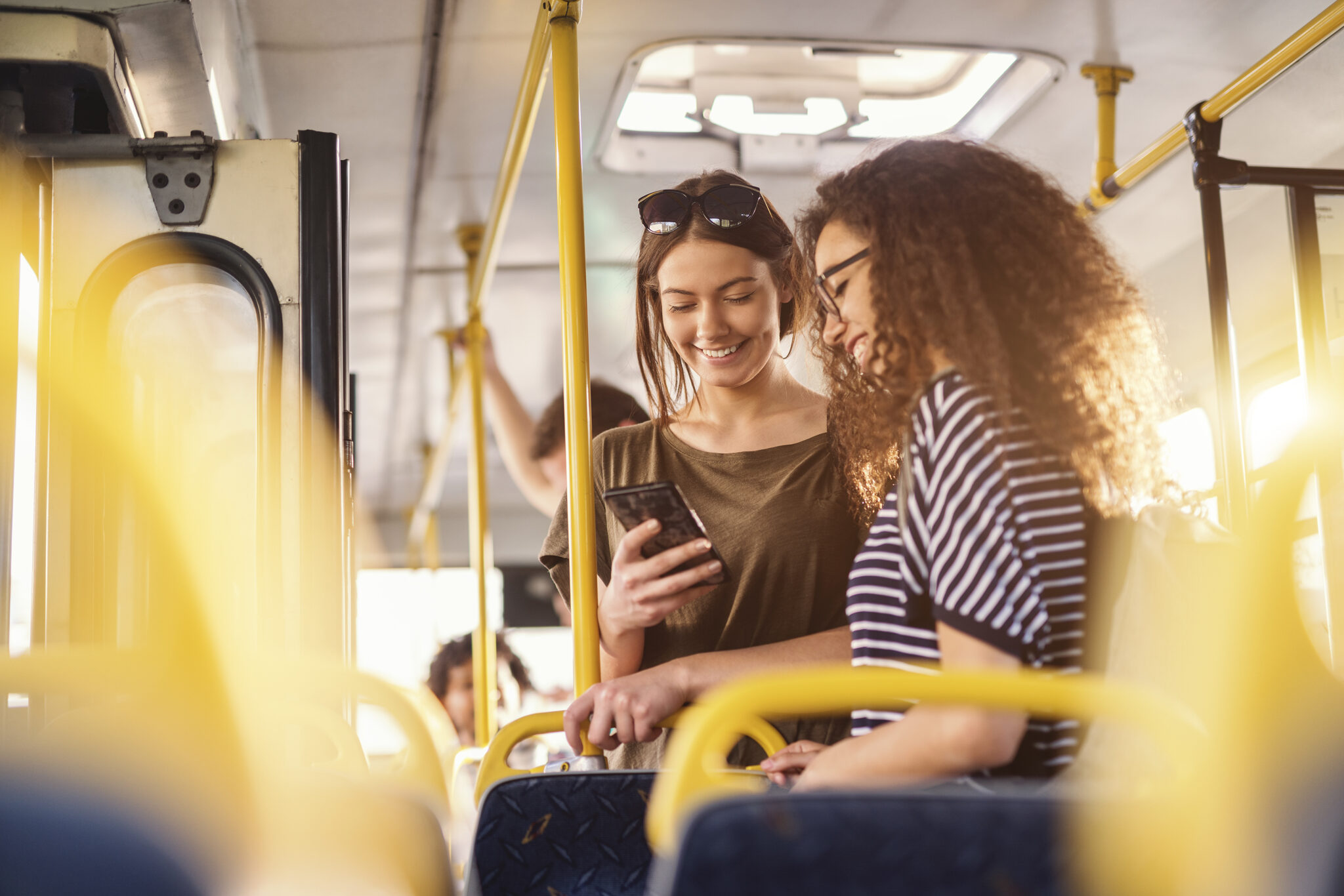 Zwei Jugendliche im Bus schauen auf ein Smartphone