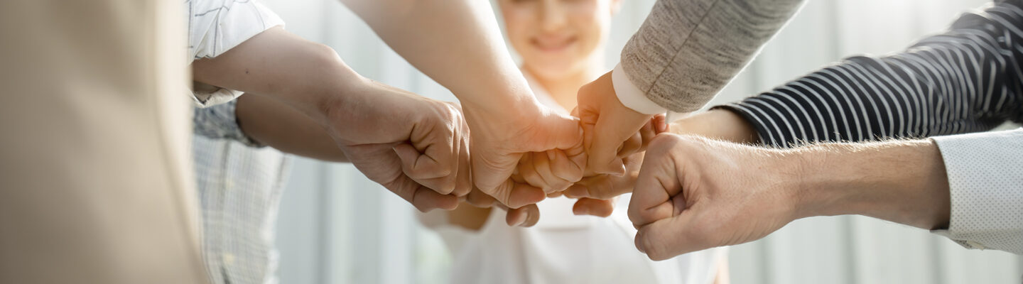 Hände verschiedener Menschen verbinden sich. Symbolbild für Teamwork.