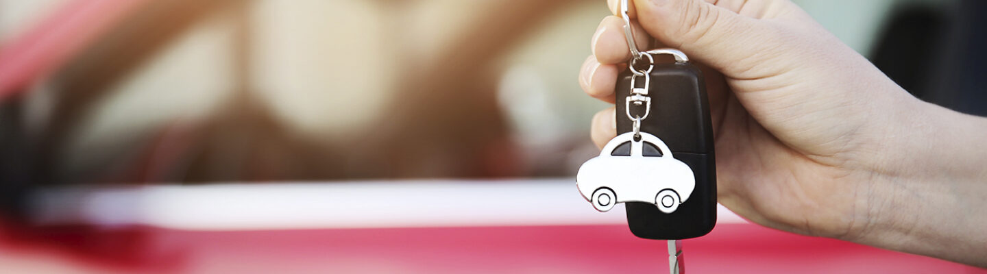 Hand hält die Schlüssel eines roten Autos