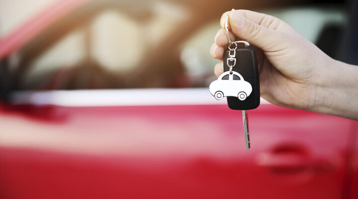 Hand hält die Schlüssel eines roten Autos