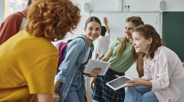 Jugendliche Schüler unterhalten sich und lachen in einem lebendigen Klassenzimmer während der Schulanfangszeit.
