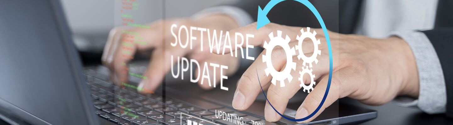 Eine Person arbeitet an einem Laptop. Über dem Bild ist eine grafische Einblendung mit der Aufschrift ‚Software Update‘, Zahnradsymbolen und einem Fortschrittsbalken zu sehen – Symbol für eine laufende Systemaktualisierung.