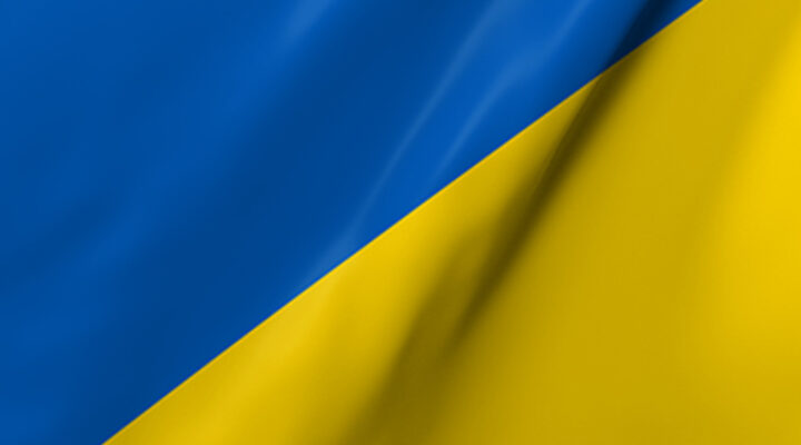 Nahaufnahme einer wehenden Ukraine Flagge in den Farben Blau, Gelb.Der Hintergrund ist Rot.